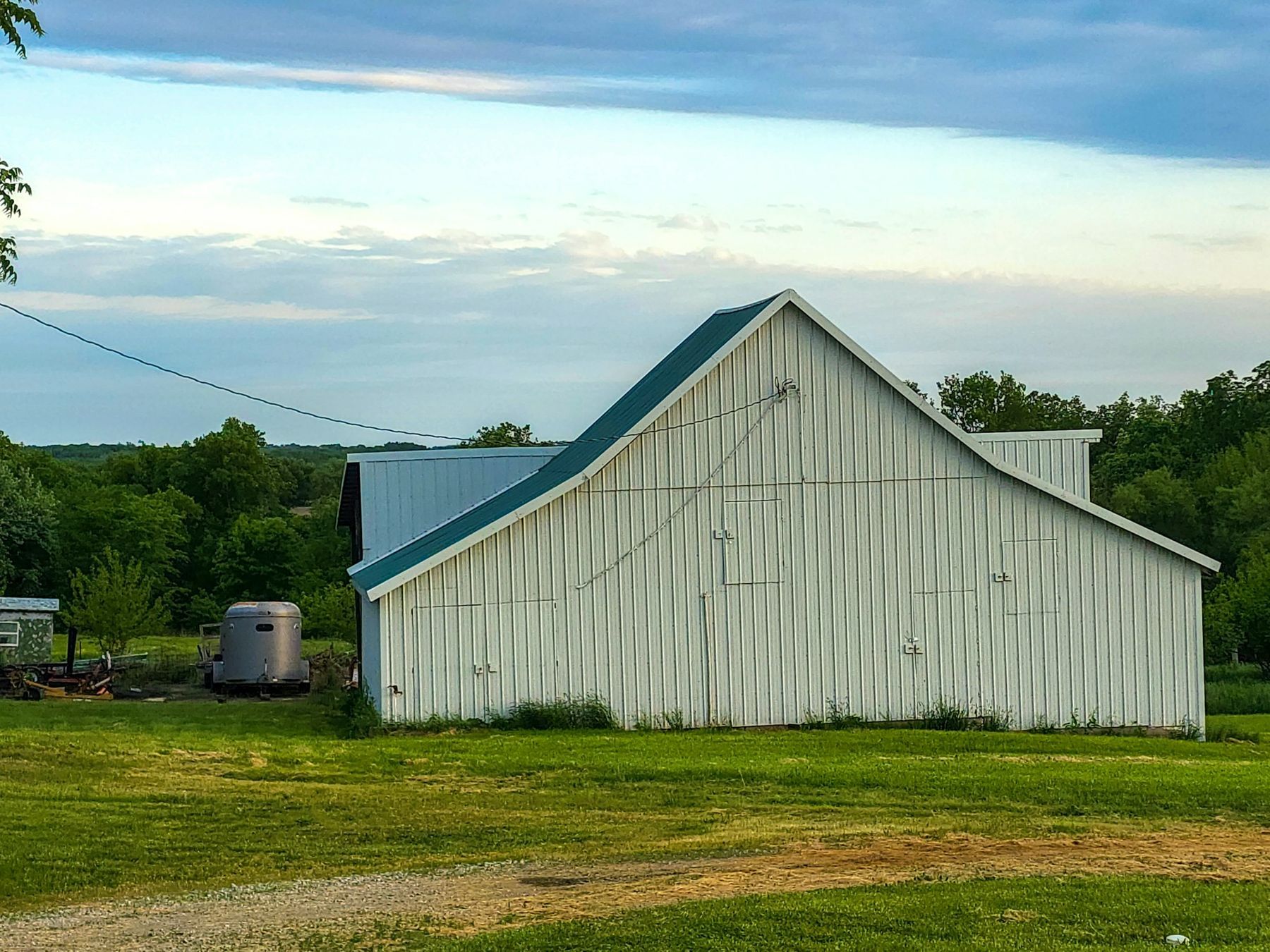 A white horse barn beside a green pasture